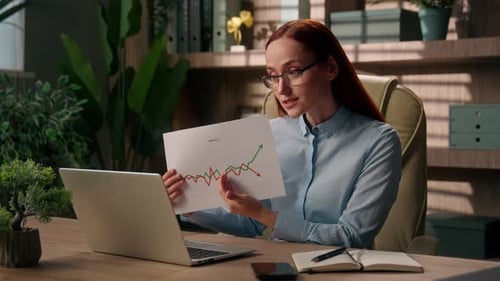 Excited Caucasian Business Woman Talking Video Call Laptop in Office Presenting Sales Results Graph