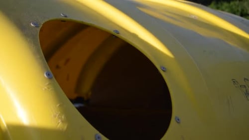 Close-up of a person's hand depositing different plastic objects in a yellow recycling bin