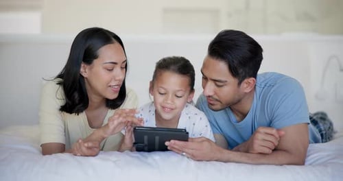 Family Enjoys Tablet Together on Bed