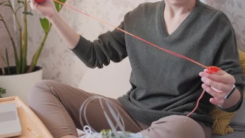 Woman Knitting at Home on Couch in Daytime