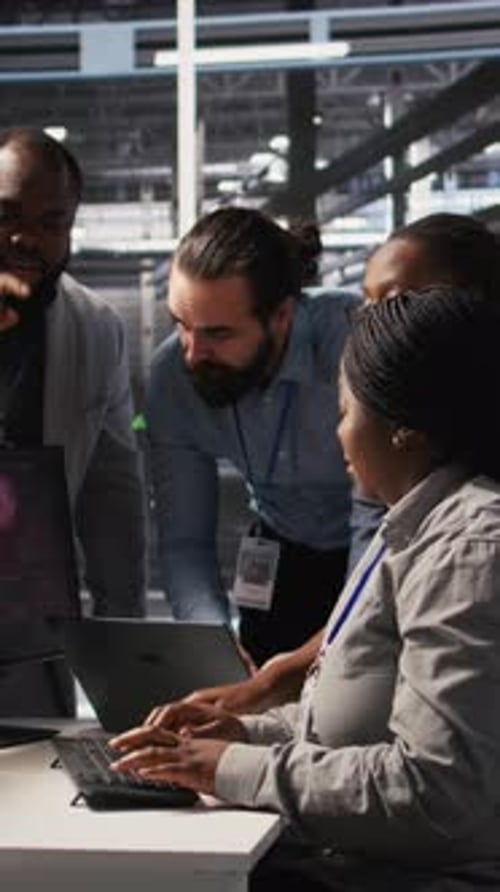 Team Gathers Around Laptop in Server Room
