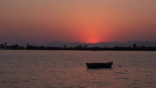 Small Boat Floating on Lake at Sunset