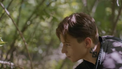 Young Tourist Shifts Branch and Pauses to Unzip Bag in Forest