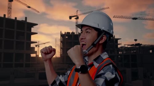 Side View Of Asian Male Engineer Screaming Goal Celebrating Working At Building Site