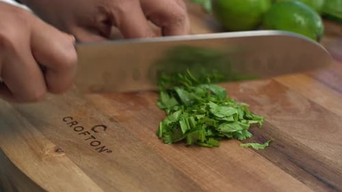 Chopping green herbs on wooden cutting board, preparing meal ingredients