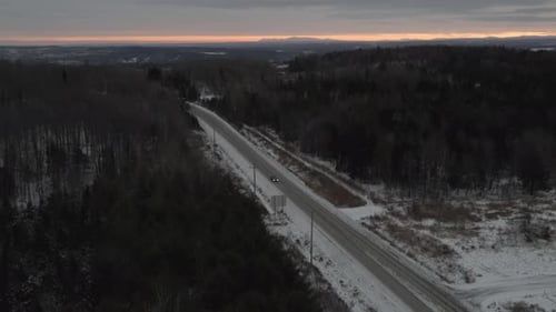 Autofahren auf verschneiter Autobahn mit kahlen Bäumen bei einem Wintersonnenaufgang — Flugdrohne, Neigung nach unten