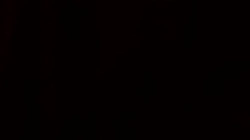Cash money falling past screen against a black background in slow motion close up