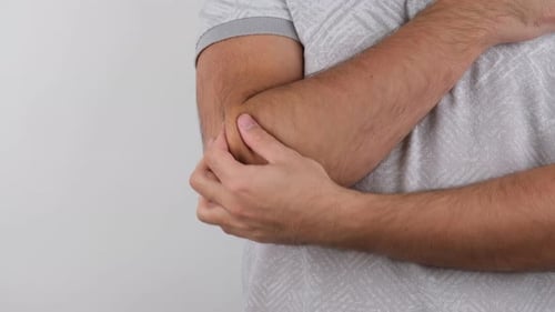 Adult Man Massaging His Elbow Against White Background