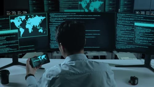 Asian Man Working With Mobile Phone While Write Code With Multiple Computer Screens In office