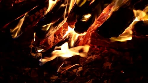 Closeup wood fire blazing in dark night, glowing embers - slow motion