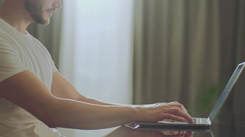 Man Typing on Laptop Computer at Home