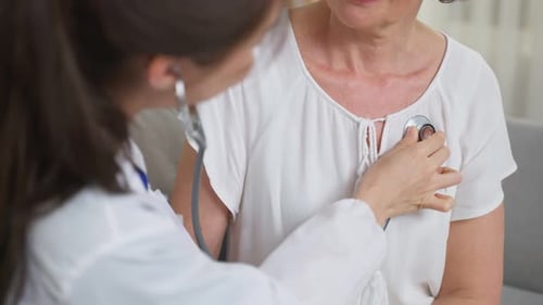 Asian caregiver nurse examine Caucasian senior woman patient at home.