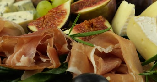 Figues, jamon, feuilles d'épinard, raisins, noix et fromages bleus sur une planche de bois. Set de snacks.