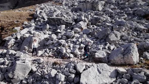 Two people walking along mountain path with rocks