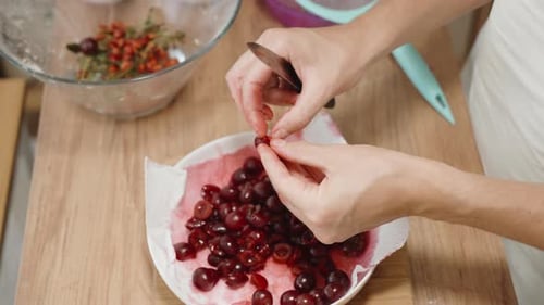 La femme retire délicatement les noyaux des cerises à l'aide d'un couteau au ralenti.