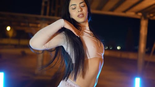 Young Woman Dancing Energetically Under a Bridge at Night