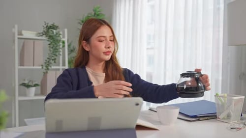 Woman Working and Pouring Coffee at Desk