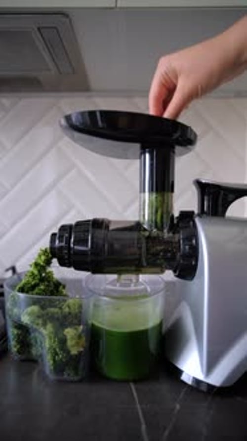 Preparing green celery juice using auger juicer in the kitchen. Making green juice. Juicing green he