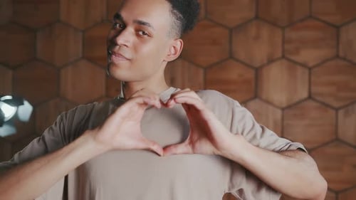 Man Makes Heart Shape with Hands Indoors