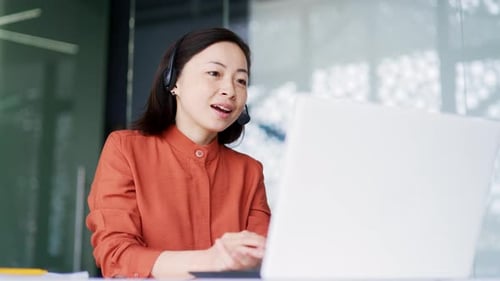 Woman with Headset Working at Computer in Office