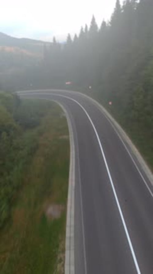 Dramatic Aerial Imagery Showcasing Winding Mountain Highway Amidst Dense Trees and Valley Landscapes