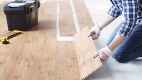 Man installing new oak wood flooring in apartment renovation project