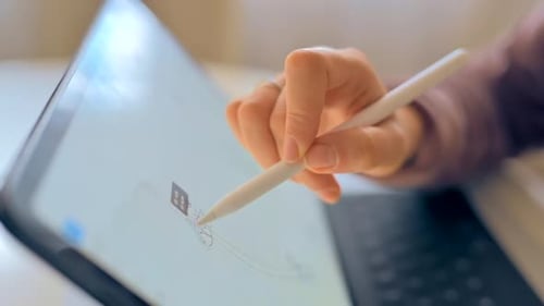 Woman drawing on a tablet with white pencil, close up