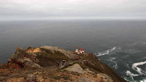 Panning shot of the Point Reyes lighthouse with lone boat on the ocean behind.