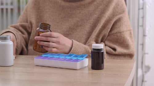 Adult Arranging Pills into Pill Organizer at Home
