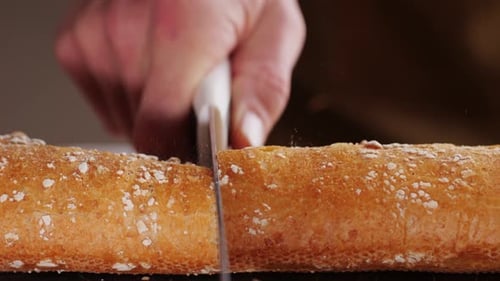 Cutting Freshly Baked Baguette with Knife, Close Up