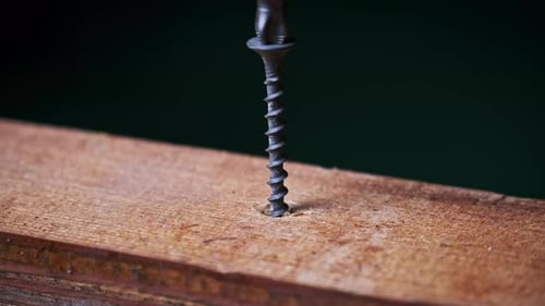 Closeup of a Screw Being Driven Into a Block of Wood with a Screwdriver