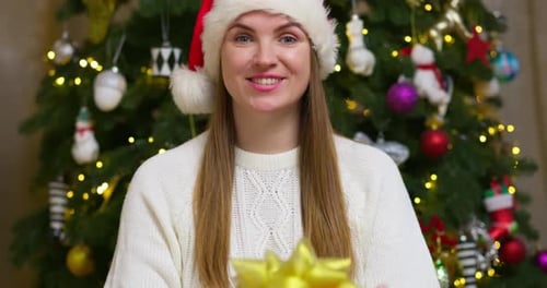 Woman in Santa Hat Giving Christmas Gift