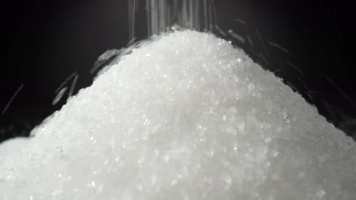 White sugar delicately cascading onto a sleek black background