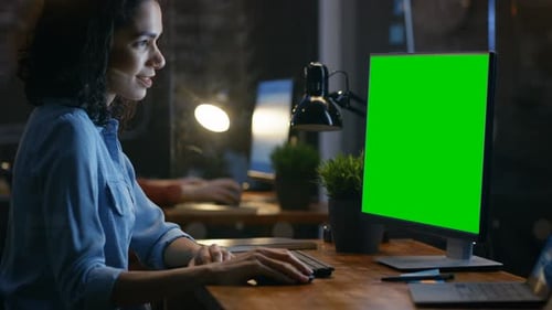 Beautiful Female Office Employee at Her Desk Works on a Mock-up Green Screen Personal Computer. Her