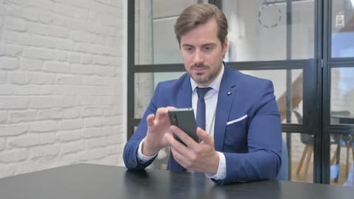 Man in Suit Uses Smartphone in Office