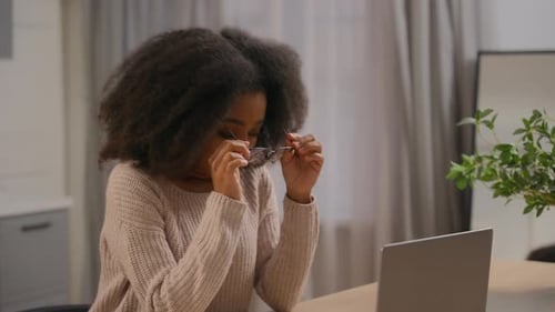 Tired Woman Taking Off Glasses at Desk Indoors
