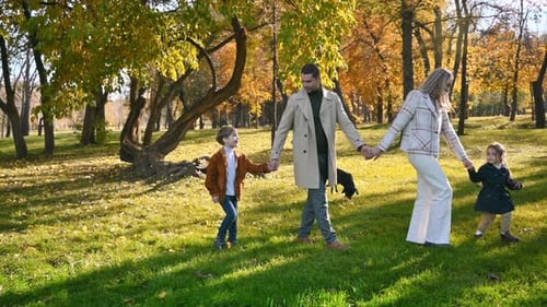 Happy family in an autumn park. Mother and father walking with daughter, son and their dog, yellowed