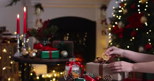 Decorating christmas gift box near christmas tree and fireplace