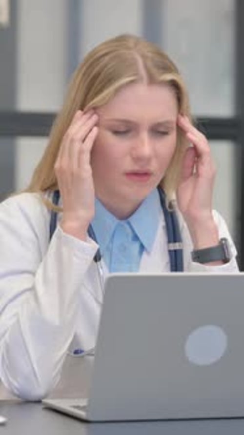 Woman Doctor Working at Desk Experiencing Headache