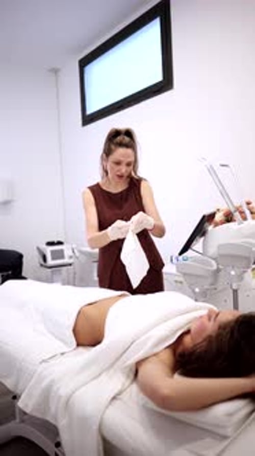 Professional female beautician in a modern clinic preparing a young woman for a non invasive cosmeti