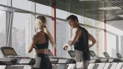 Fitness Couple Running on Treadmill Machine in Gym Club Together. Handsome Man