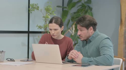 Woman and Man Collaborating on a Laptop in Office