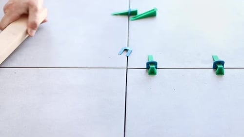 Tapping White Tile with Wooden Plank