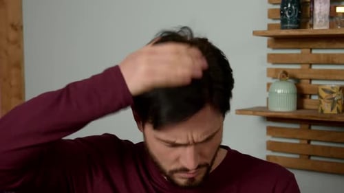 Man Indoors Applying Hair Product to Hair
