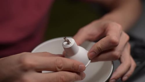 Nahaufnahme: Hände eines unbekannten Mannes, der eine Gu10-LED-Lampe in den Lampensockel überprüft, Konzept des Übergangs zu