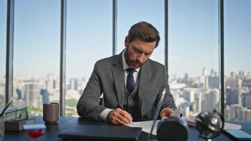Professional Man Reviews Documents in Modern Office