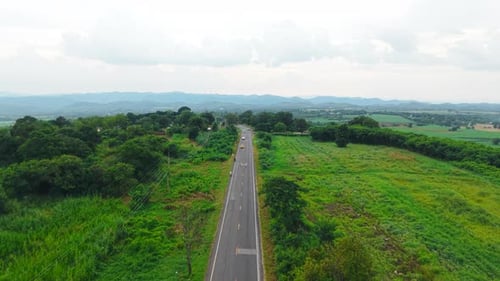 Vehicles Traveling on a Paved Road Through a Rural Landscape