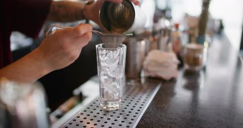 Bartender Making Cocktail by Pouring Drink into Glass