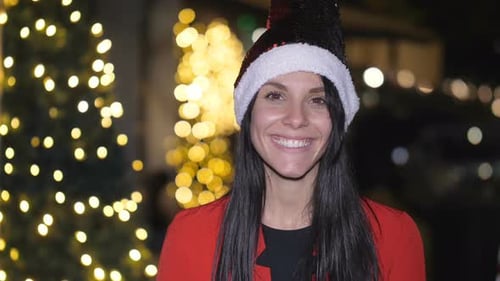 Smiling Woman With Santa Hat In Front Of Christmas Tree