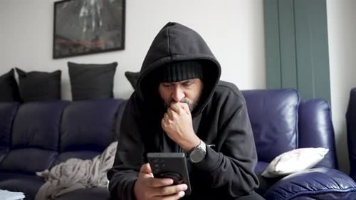 South asian man checking phone looking worried at home